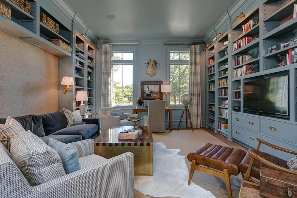 Blue-grey library with comfy suede and leather furniture. The library has an old-world mixed with contemporary feel. 