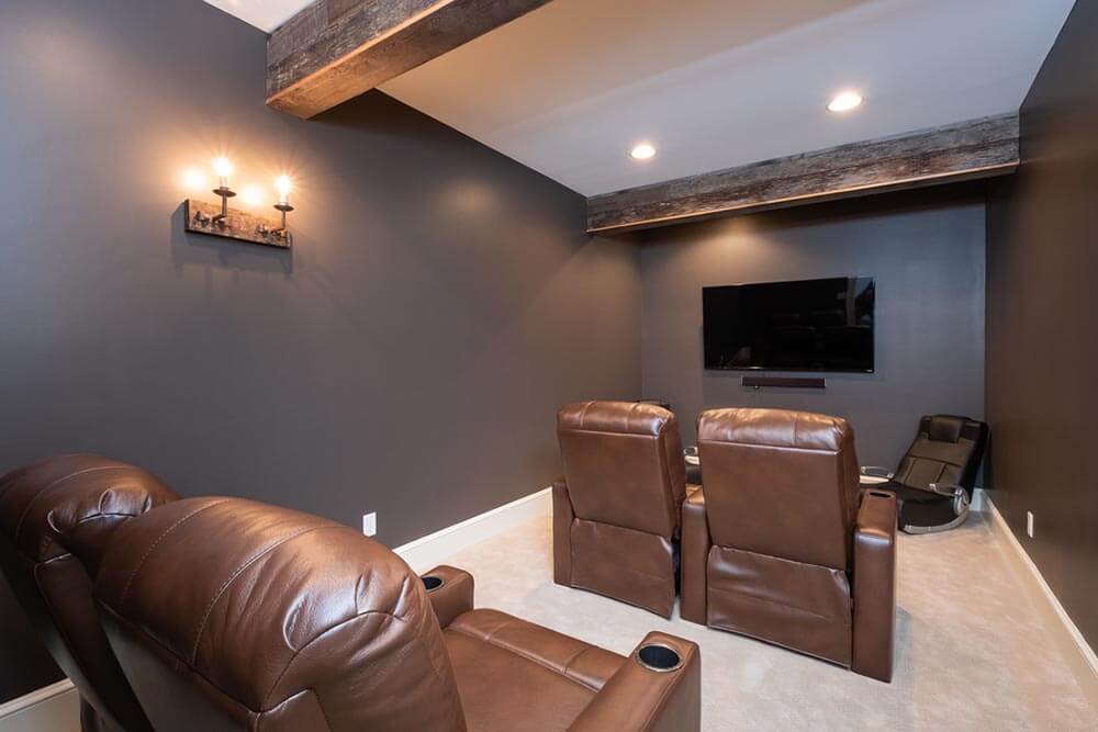 dark colored theater room with two large exposed beams and some unique industrial pipe lighting