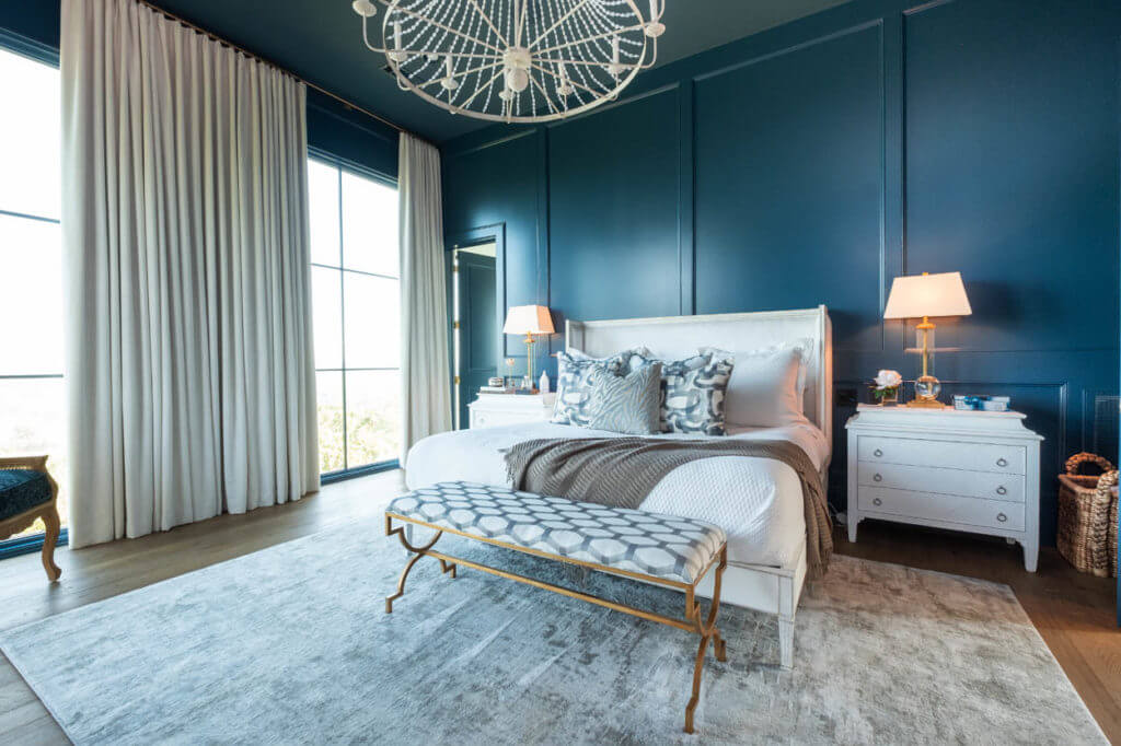 Beautiful, deep blue walls with matching casing. Beige floor to ceiling drapes covering floor to ceiling windows. Classical white furniture with gold accents.